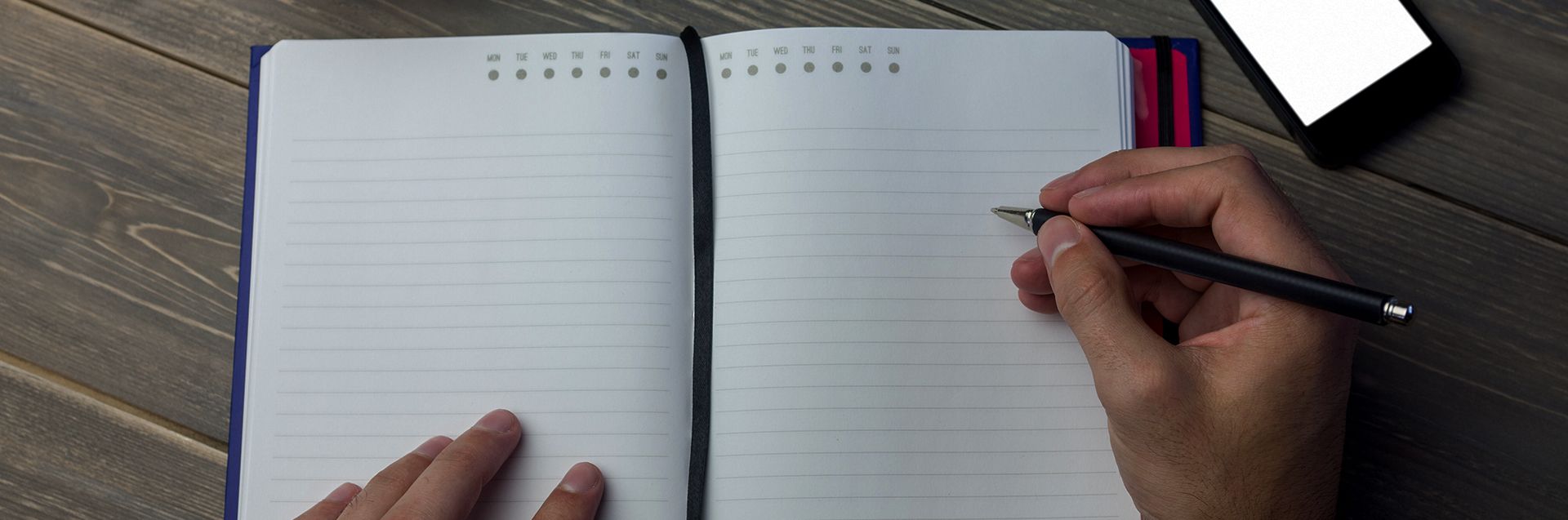 Person writing on a diary at the desk